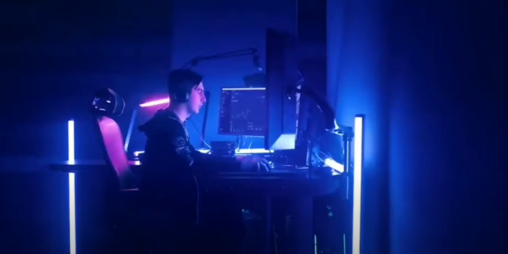 Michael Grzesiek wearing an earphone, sitting in a dark room with neon lights